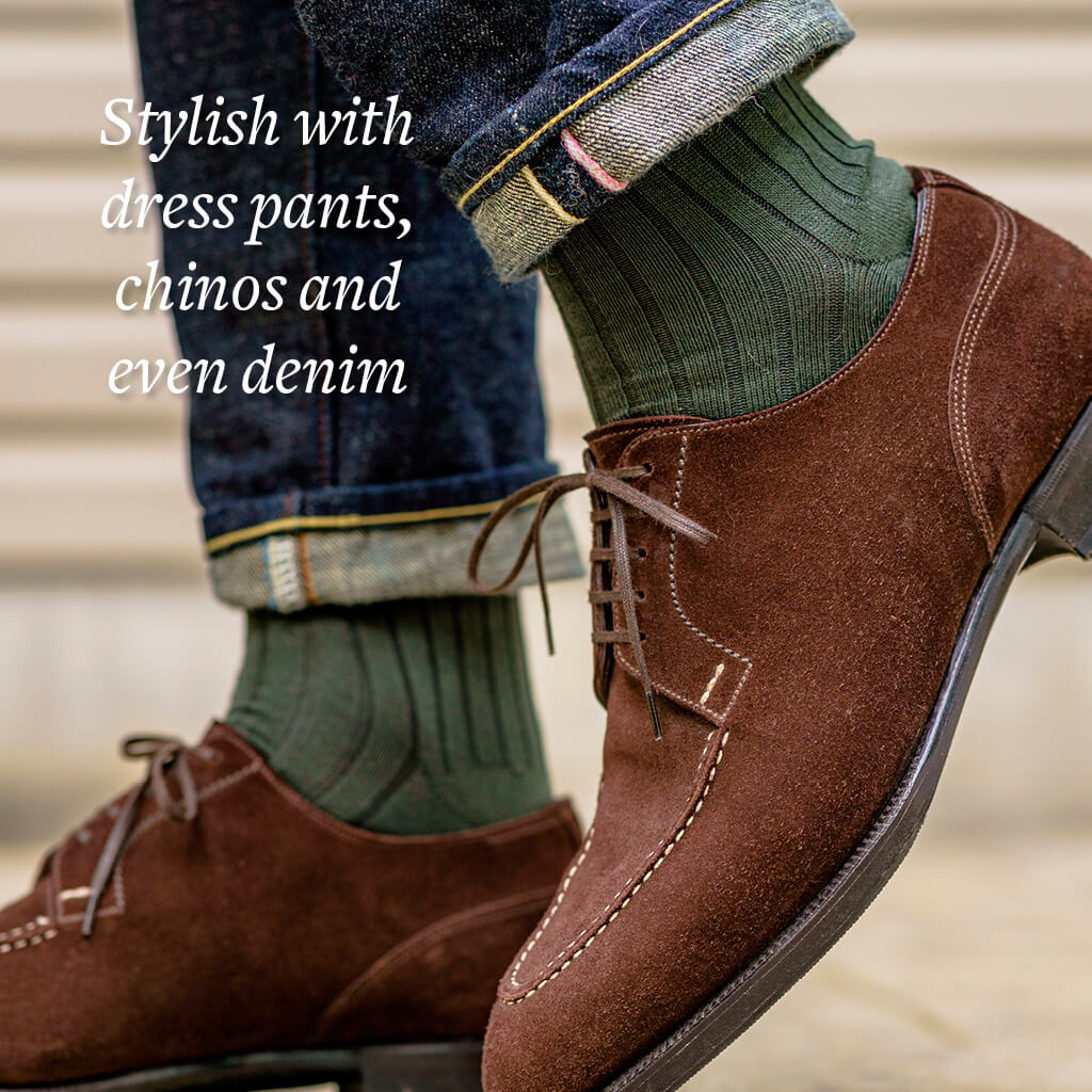 close up of man walking while wearing olive green ribbed dress socks with dark cuffed jeans and brown suede dress shoes