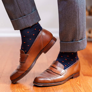 man walking on hardwood floors wearing navy wool dress socks decorated with bright orange polka dots