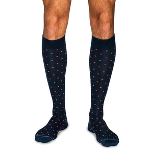 model wearing navy over the calf dress socks decorated with orange dots