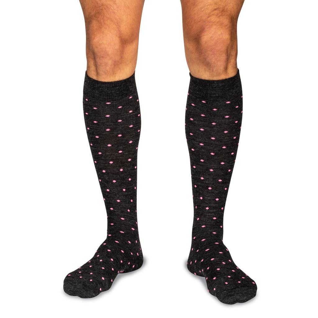 model wearing dark grey over the calf dress socks decorated with bright pink dots