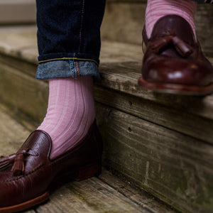 man wearing pink dress socks with dark wash jeans and brown tassel loafers