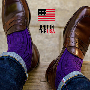 man wearing bright purple dress socks with dark jeans and brown penny loafers