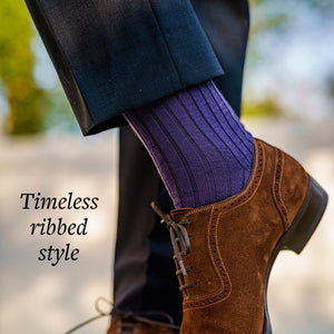 man crossing ankles wearing purple wool dress socks with charcoal pants and brown suede shoes