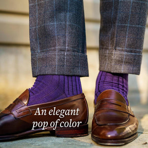man standing wearing purple ribbed dress socks with grey trousers and brown penny loafers