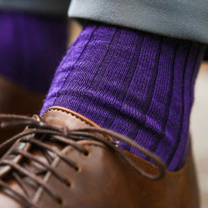 close up photo of man wearing ribbed merino wool purple dress socks with grey pants and brown dress shoes