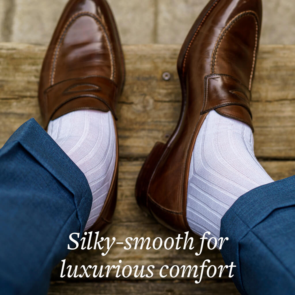 man wearing white dress socks with light brown penny loafers and blue cuffed trousers